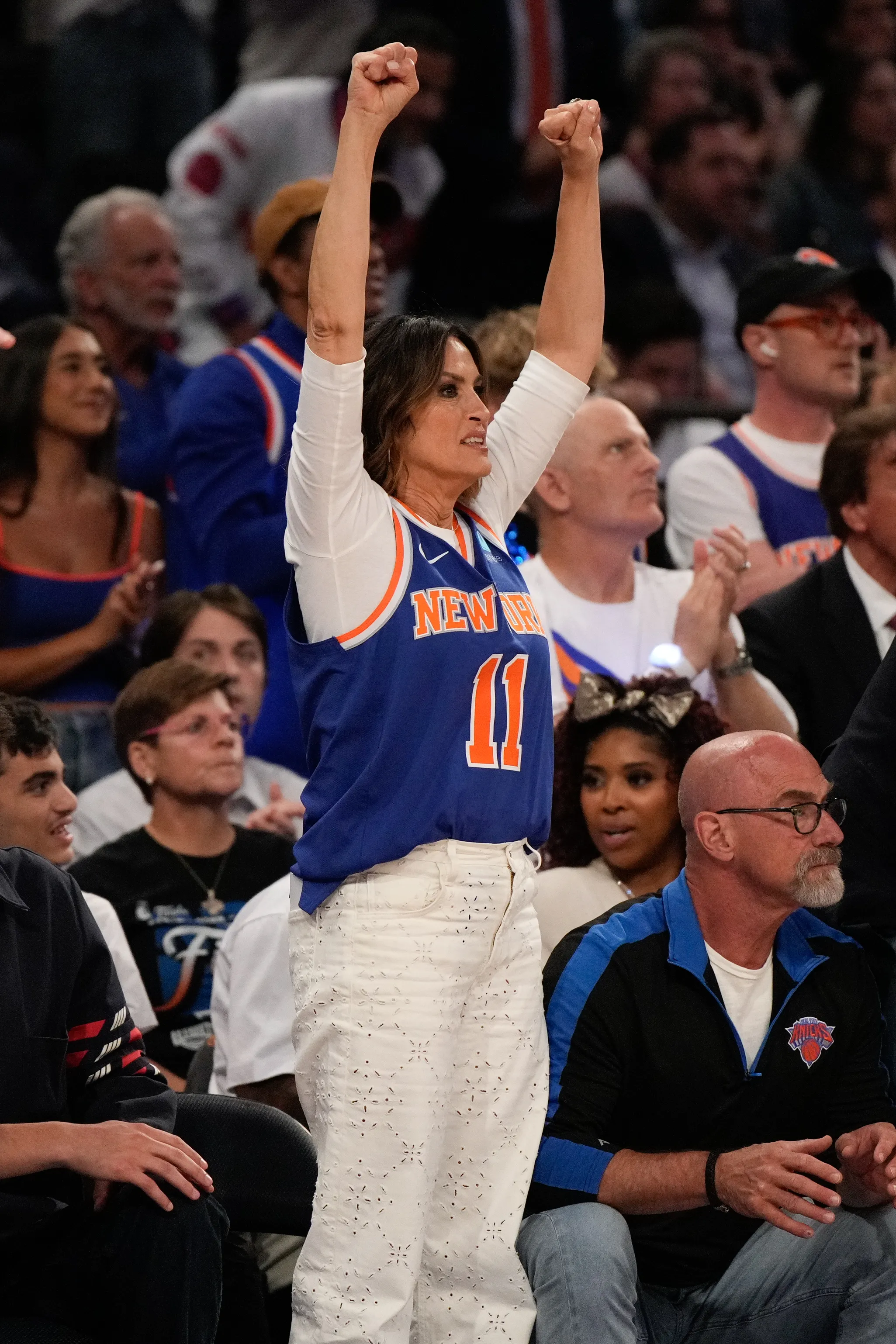 Mariska Hargitay cheering with her arms raised while wearing a New York Knicks jersey.
