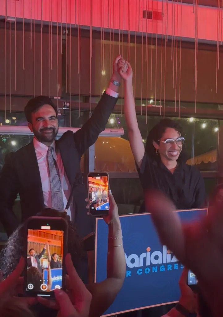 Mayor Zohran Mamdani and Darializa Chevalier holding hands aloft at a watch party.