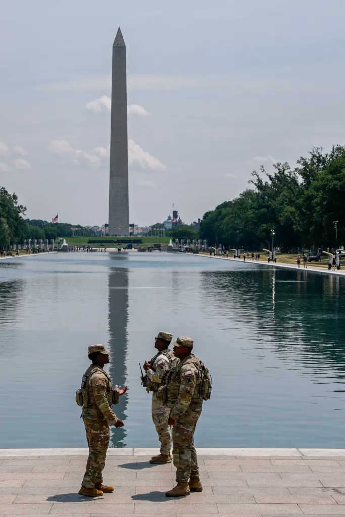National Guard members patrol the Lincoln Memorial Reflecting Pool, with the Washington Monument in the background.