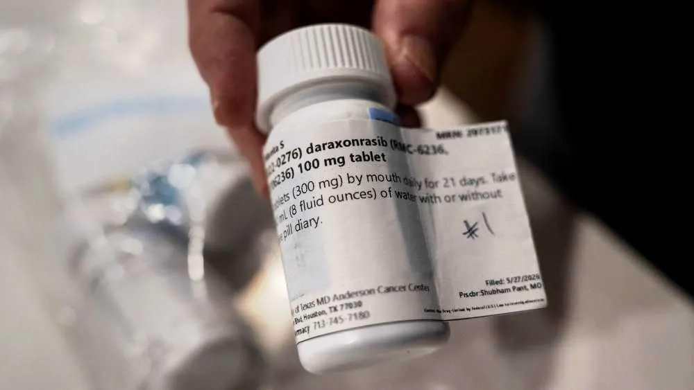 A person holding a bottle of daraxonrasib, a pancreatic cancer drug.