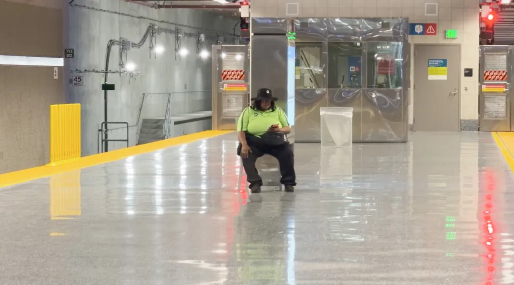 A Metro rider sits on a stool on a platform in a Los Angeles subway station.