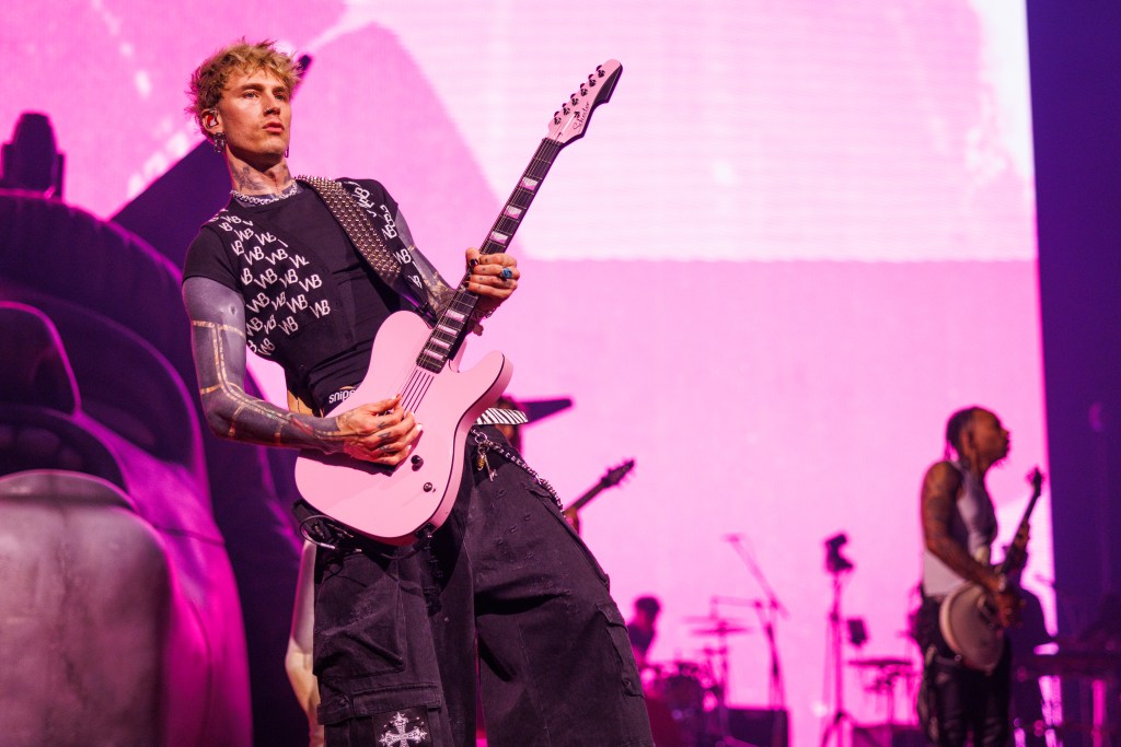 MGK performs onstage playing a pink electric guitar.