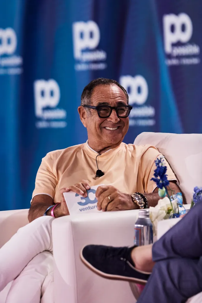 Michael Kassan smiling while speaking at an event, holding a card that reads 