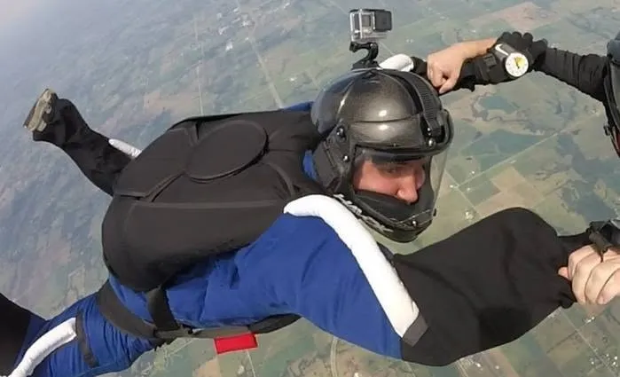 Dave Hershberger skydiving in a black and blue suit and helmet.