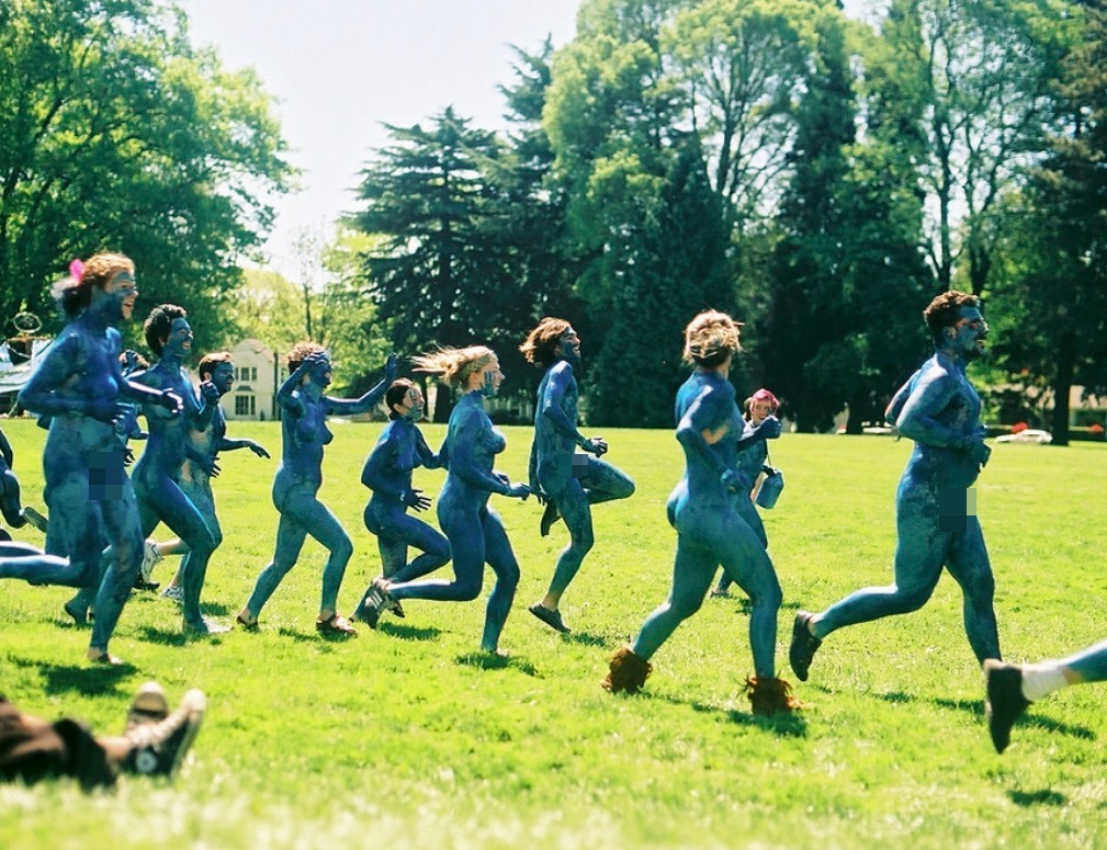 People painted blue running in a field.