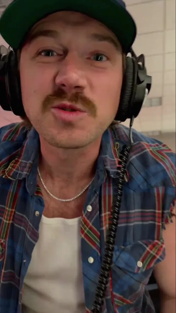 Morgan Wallen wearing headphones and a plaid shirt.