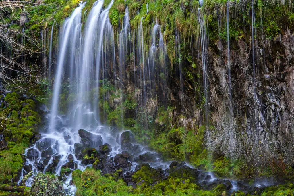 Mossbrae Falls in Dunsmuir cascades over a moss-covered rock face into a rocky stream below.