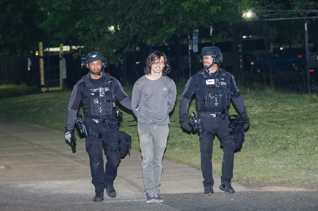 Two law enforcement officers escort an arrested protester.
