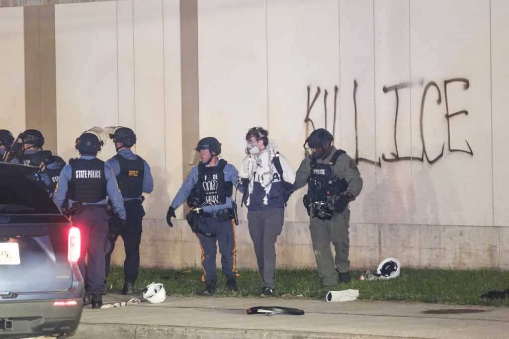 Police arrest a protestor wearing a gas mask outside Delaney Hall, an ICE detainment center, with
