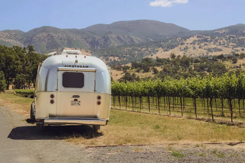 An Airstream camper parked next to rows of grapevines at Nelson Family Vineyards.