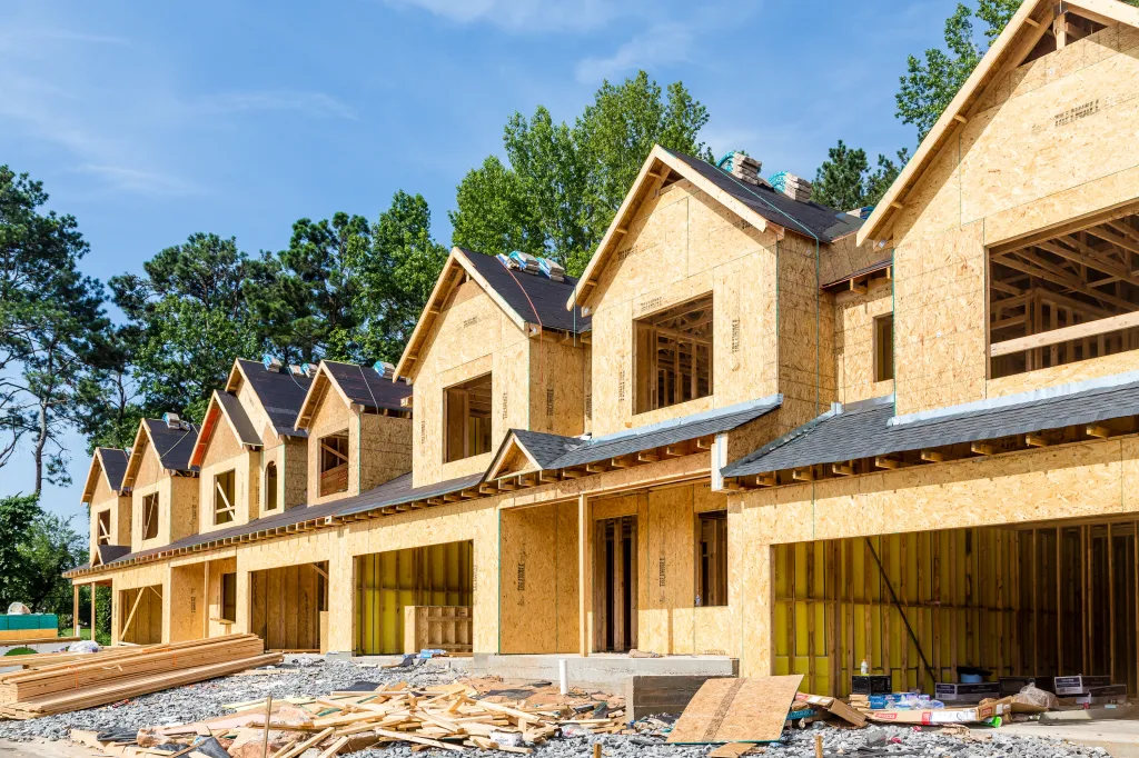 Row houses under construction, with wooden sheathing and asphalt roofs.