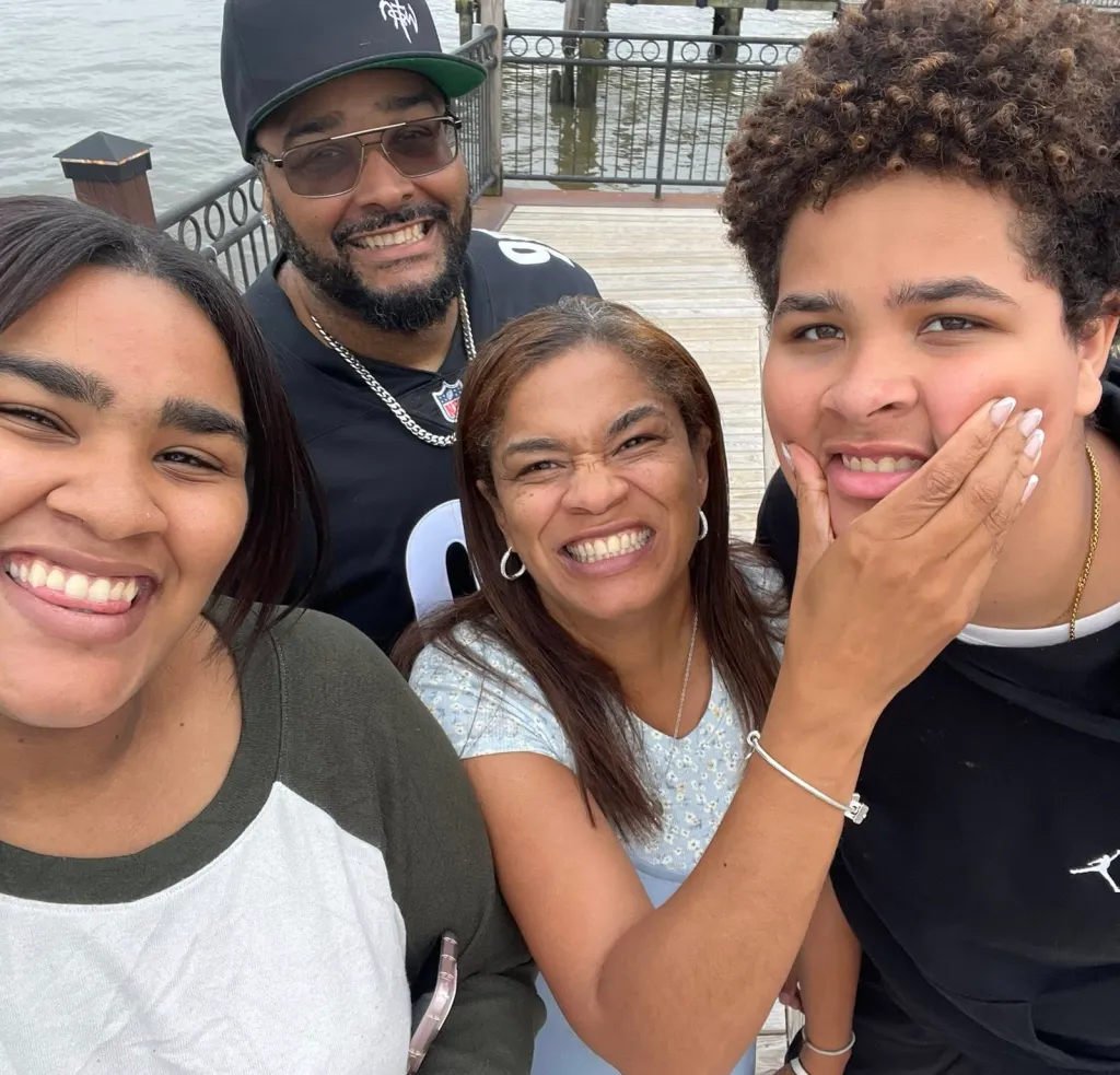 Officer Gregory Toone and his family, Alina, Yenny Disla-Toone, and Jeremiah, smiling on a dock.