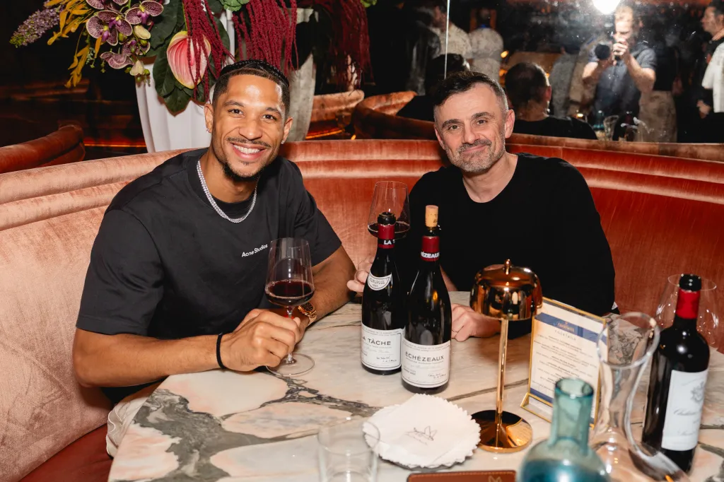 Karl-Anthony Towns and Gary Vaynerchuk smiling with glasses of red wine at the New York Knicks championship celebration.