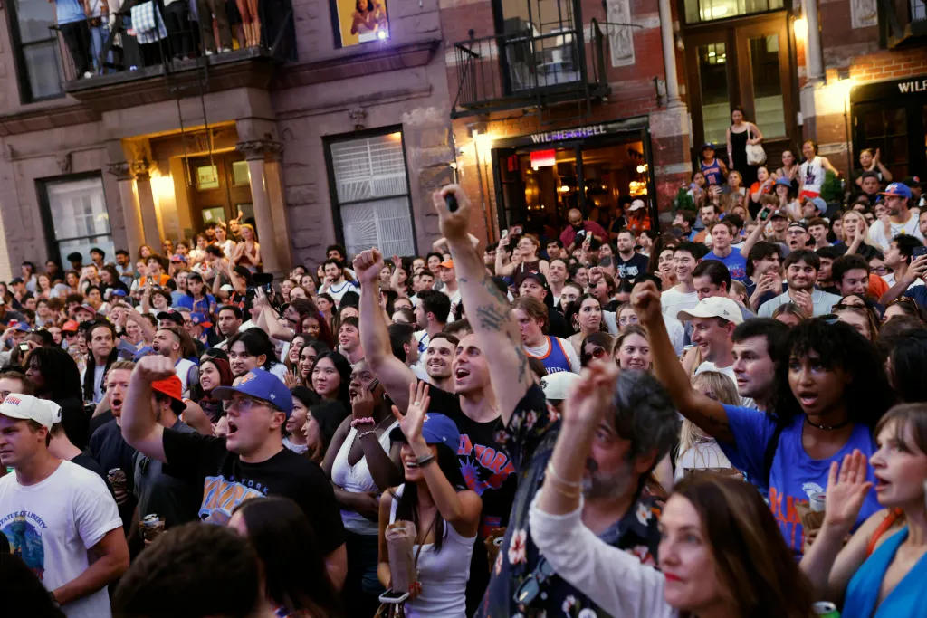 New York Knicks fans watch Game 5 of the NBA Finals against the San Antonio Spurs on the street.