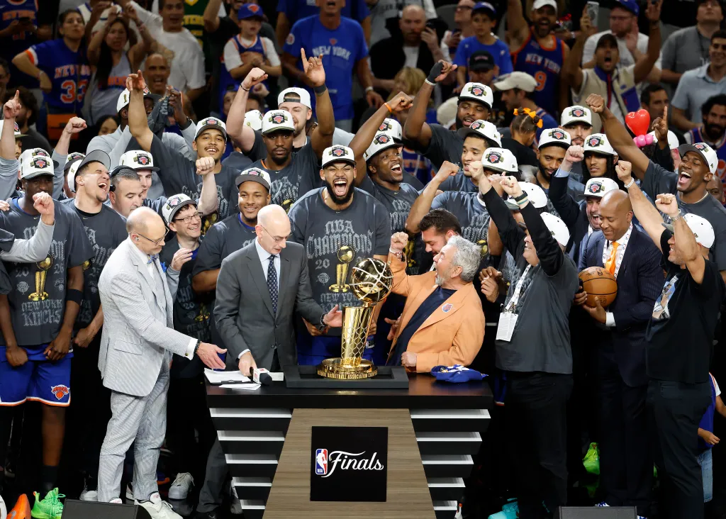 The New York Knicks team and owner James Dolan celebrate with the 2026 NBA Finals trophy.