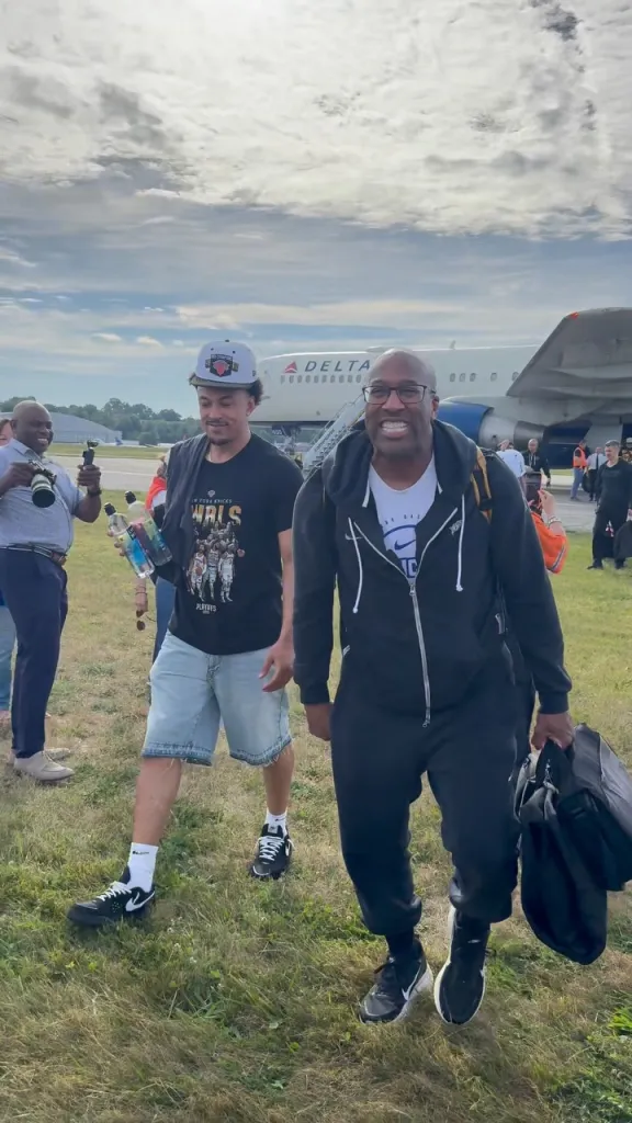 Two men walk on grass away from a Delta airplane.