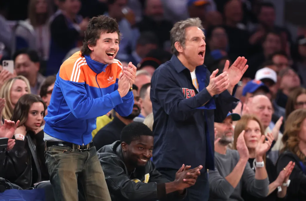 Actors Timothée Chalamet and Ben Stiller clap courtside at a Knicks vs. Hawks game.