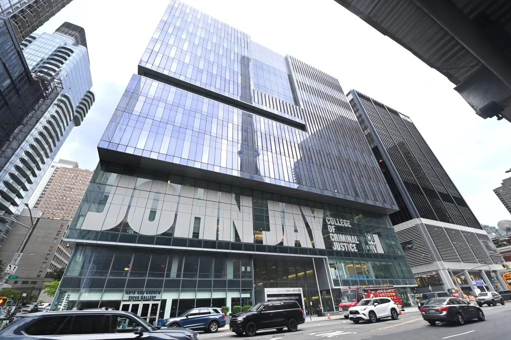 The glass facade of John Jay College of Criminal Justice with its name visible on the building.