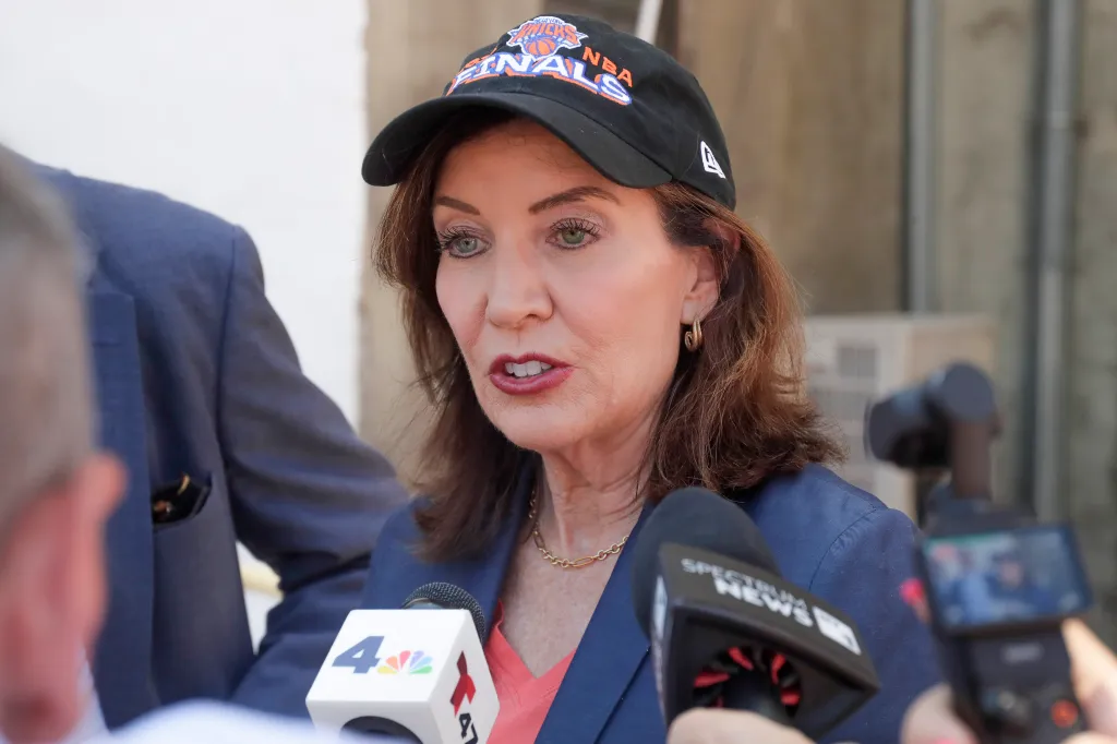 New York State Governor Kathy Hochul speaks while wearing an NBA Finals cap.