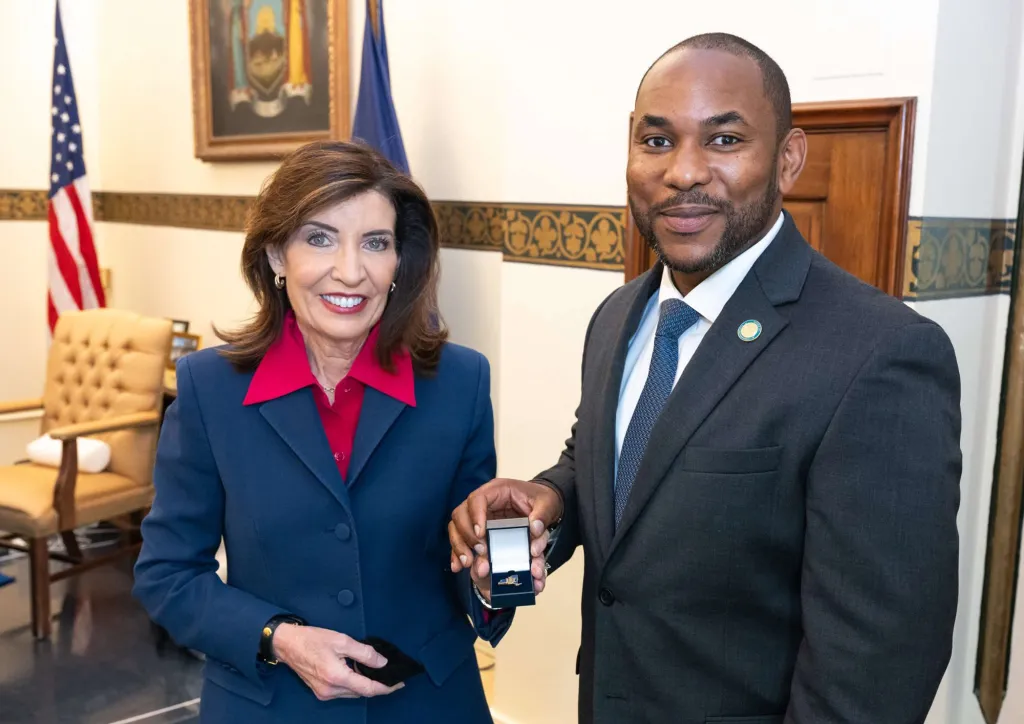 Governor Kathy Hochul and John Kagia posing with an open ring box.