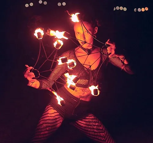 Nicole Najlis performing with fire props at night.