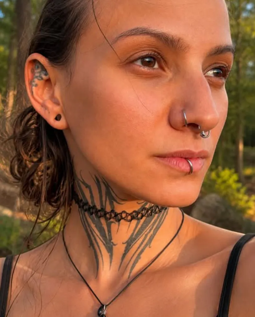 Nicole Najlis with facial piercings, neck tattoos, and a choker.