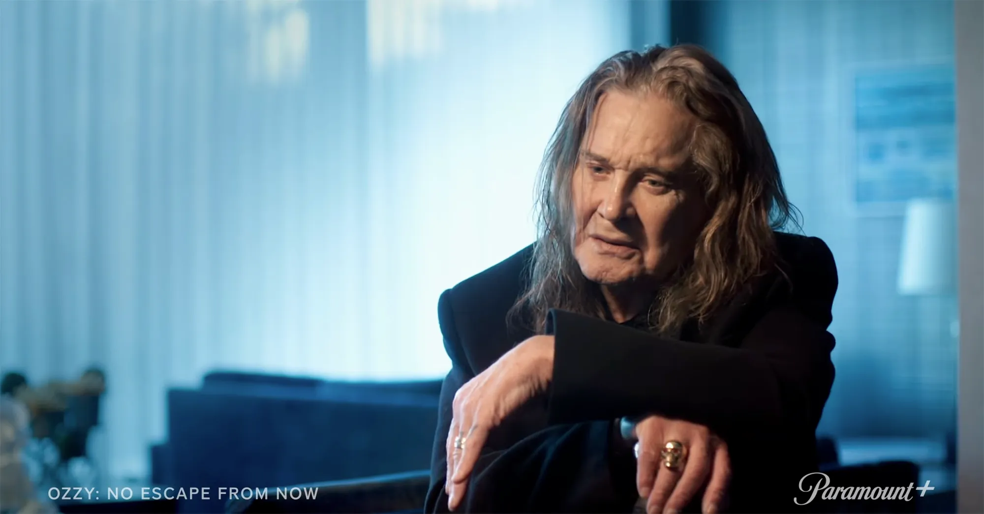 Ozzy Osbourne sitting and looking away in a black suit.