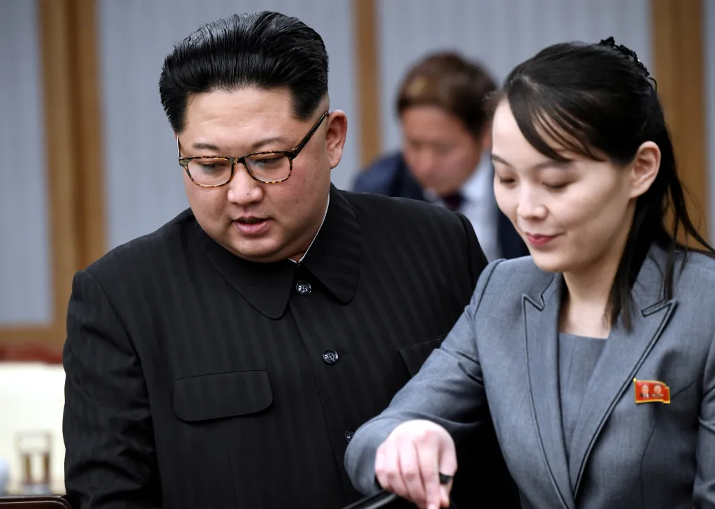 Kim Jong Un and Kim Yo Jong looking down during a meeting.