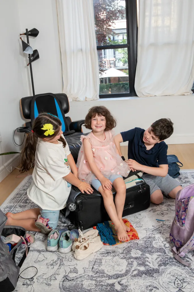 Three children packing a suitcase for an 11-week trip to Europe.