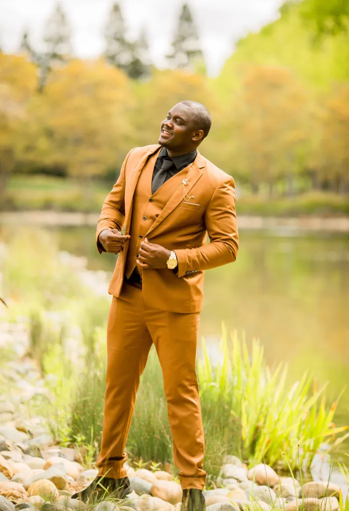 Nurse Lartey Solomon in a tan suit standing by a pond.