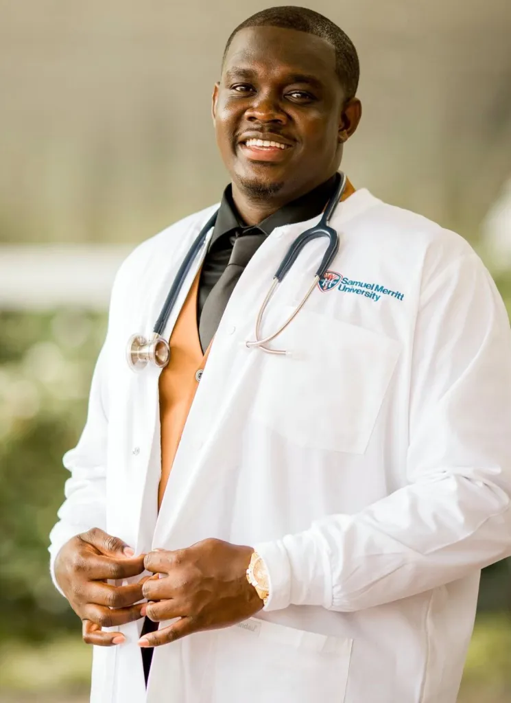 Nurse Lartey Solomon wearing a white lab coat, tie, and stethoscope.
