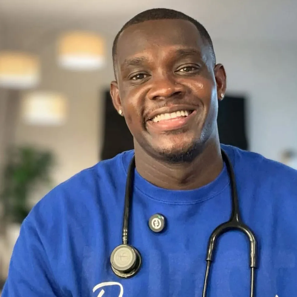 Lartey Solomon, a nurse, smiling and wearing a blue shirt and stethoscope.