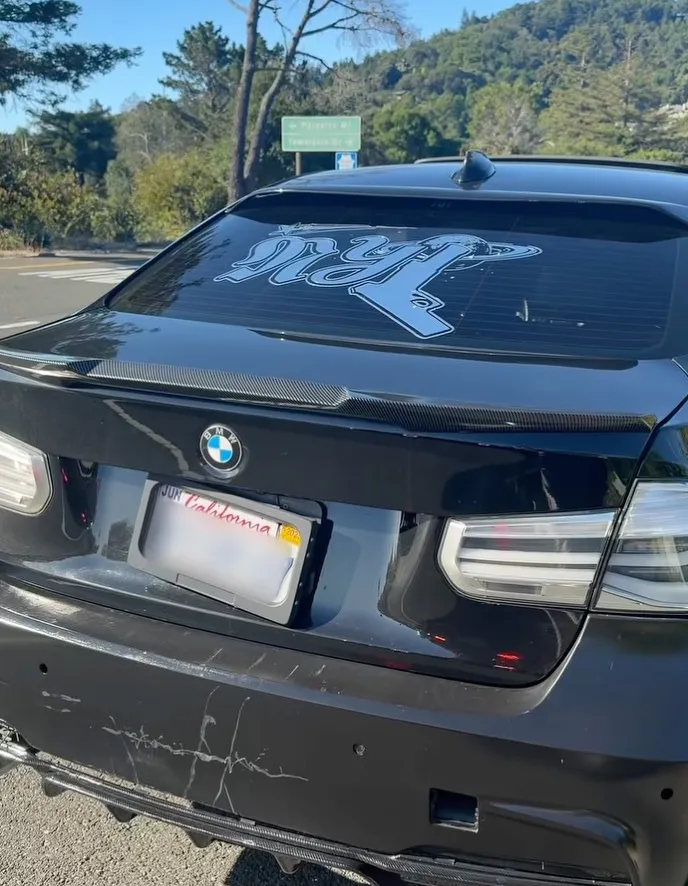 Black car with a gadget obscuring its California license plate.