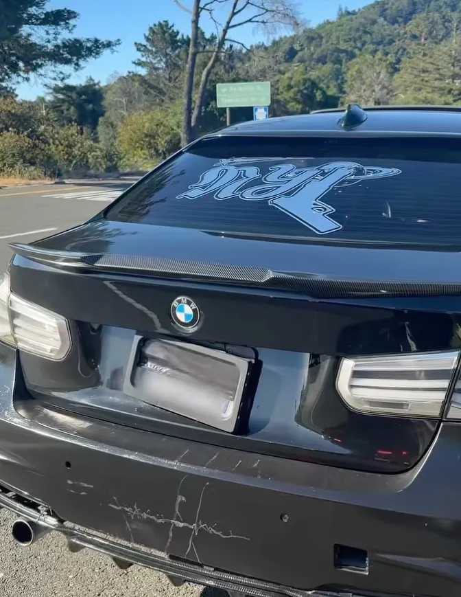 A license plate obscured by a mechanical cover on the back of a black BMW.