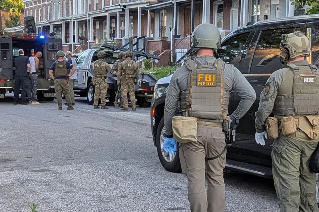 FBI agents and a Lenco BearCat armored vehicle on a street in front of row houses during 