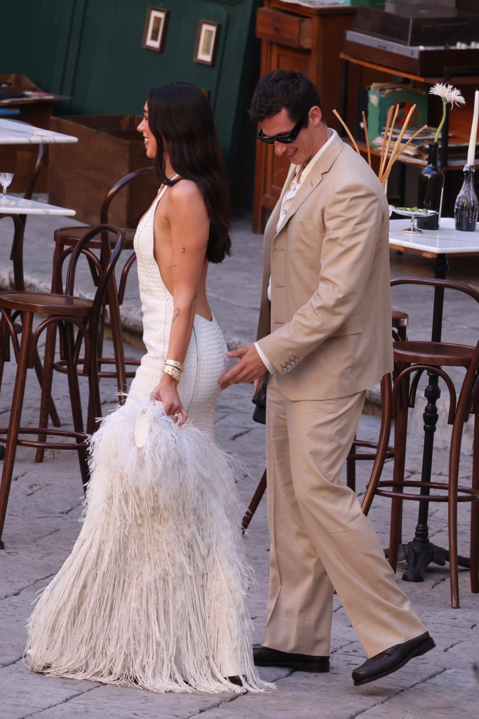 Dua Lipa in a white feathered dress and Callum Turner in a beige suit enjoying pre-wedding celebrations in Palermo.