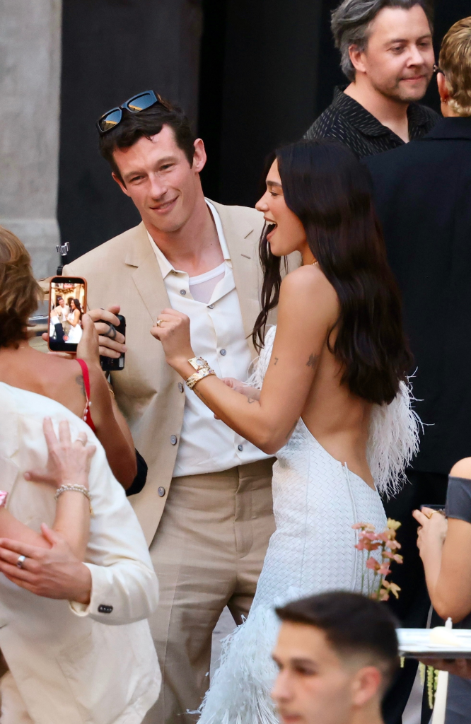Dua Lipa in a white feathered gown and Callum Turner in a beige suit enjoying pre-wedding celebrations.