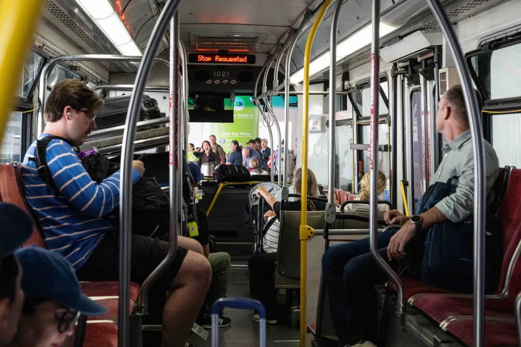 Passengers aboard a rideshare bus at LAX airport.