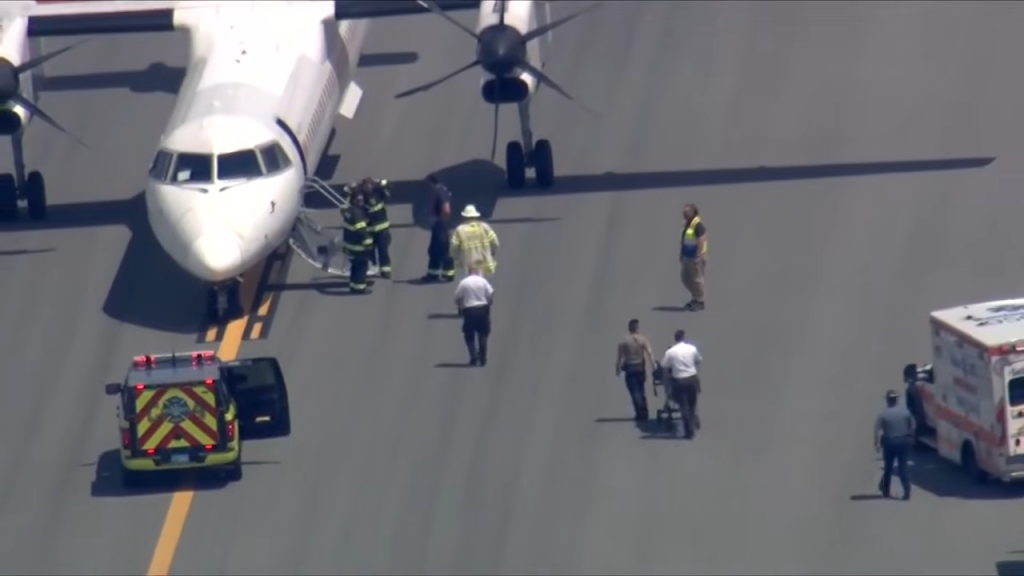Emergency personnel and vehicles on a tarmac next to a white airplane.