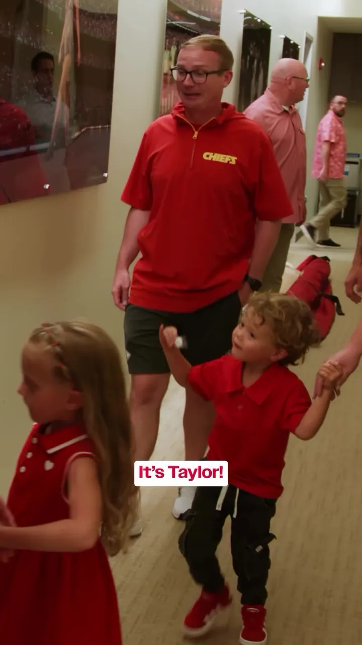 A young boy in a red shirt pointing to a photo and saying