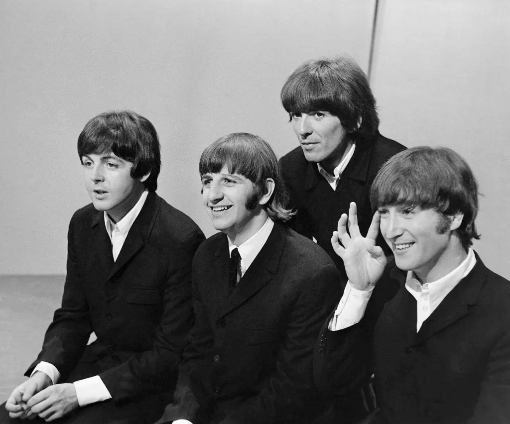 The Beatles smiling and sitting on the set of 
