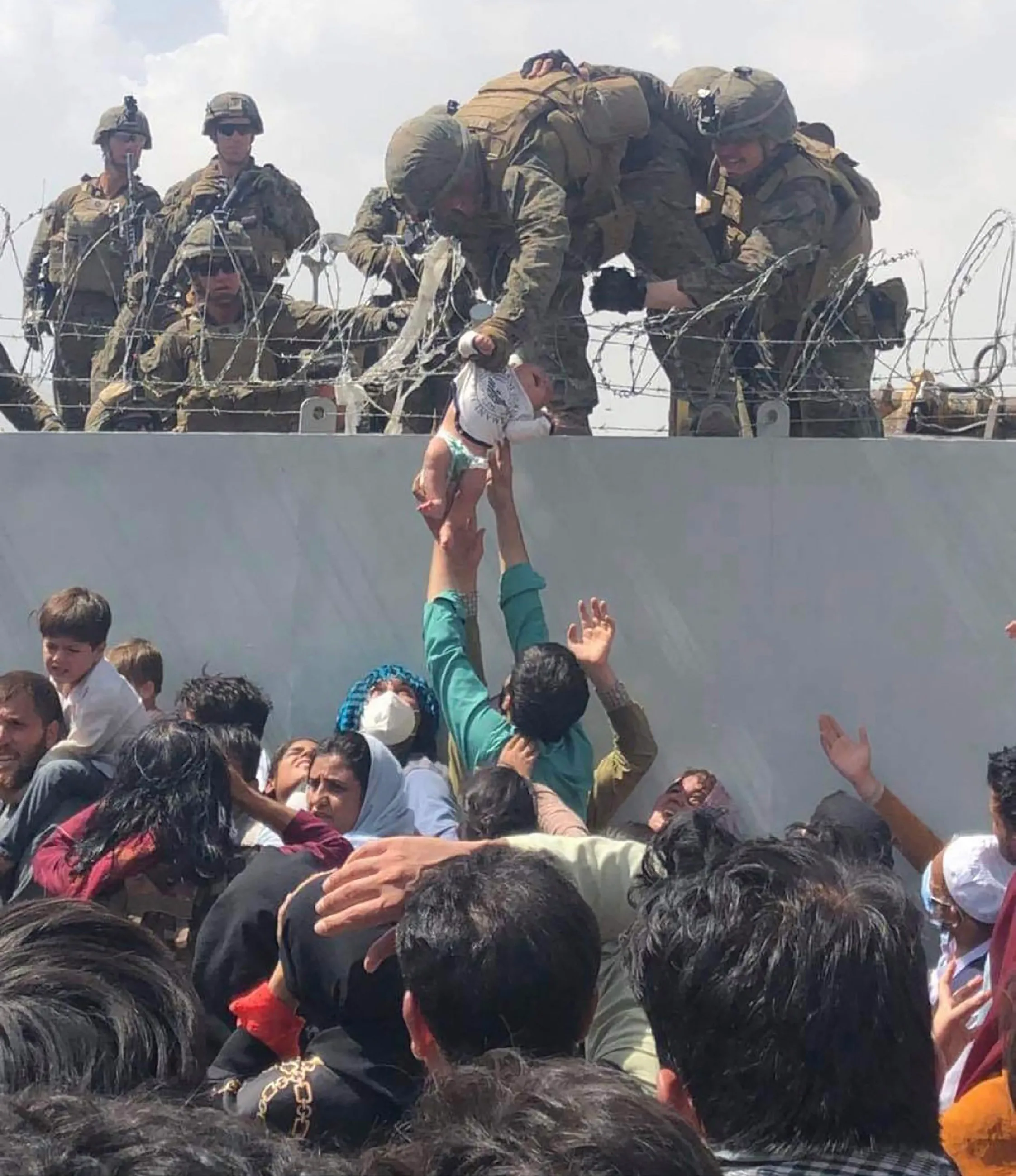 A US Marine pulls an infant over a barbed wire fence during an evacuation at Hamid Karzai International Airport in Kabul, Afghanistan, on Aug. 19, 2021.