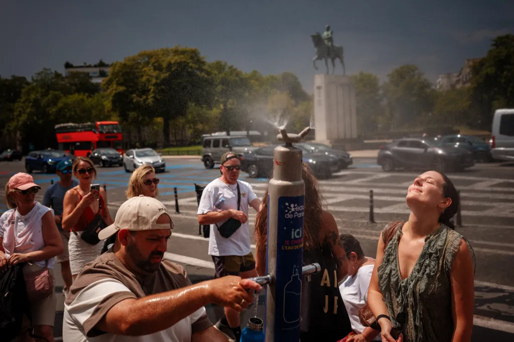 People cooling off at a mist fountain during a heatwave in Paris.