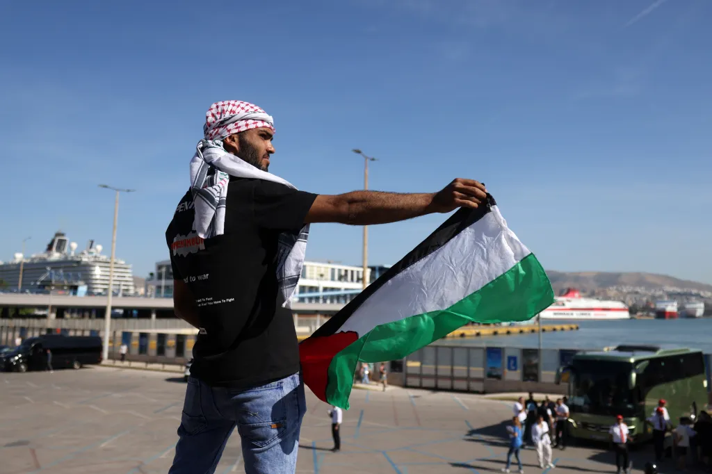 A man holding a Palestinian flag protests the arrival of an Israeli cruise ship at a Greek port.