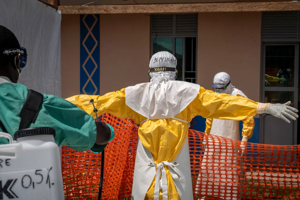 A health worker sprays a colleague in a yellow protective suit as they prepare to remove their PPE at an Ebola treatment center in Bunia.