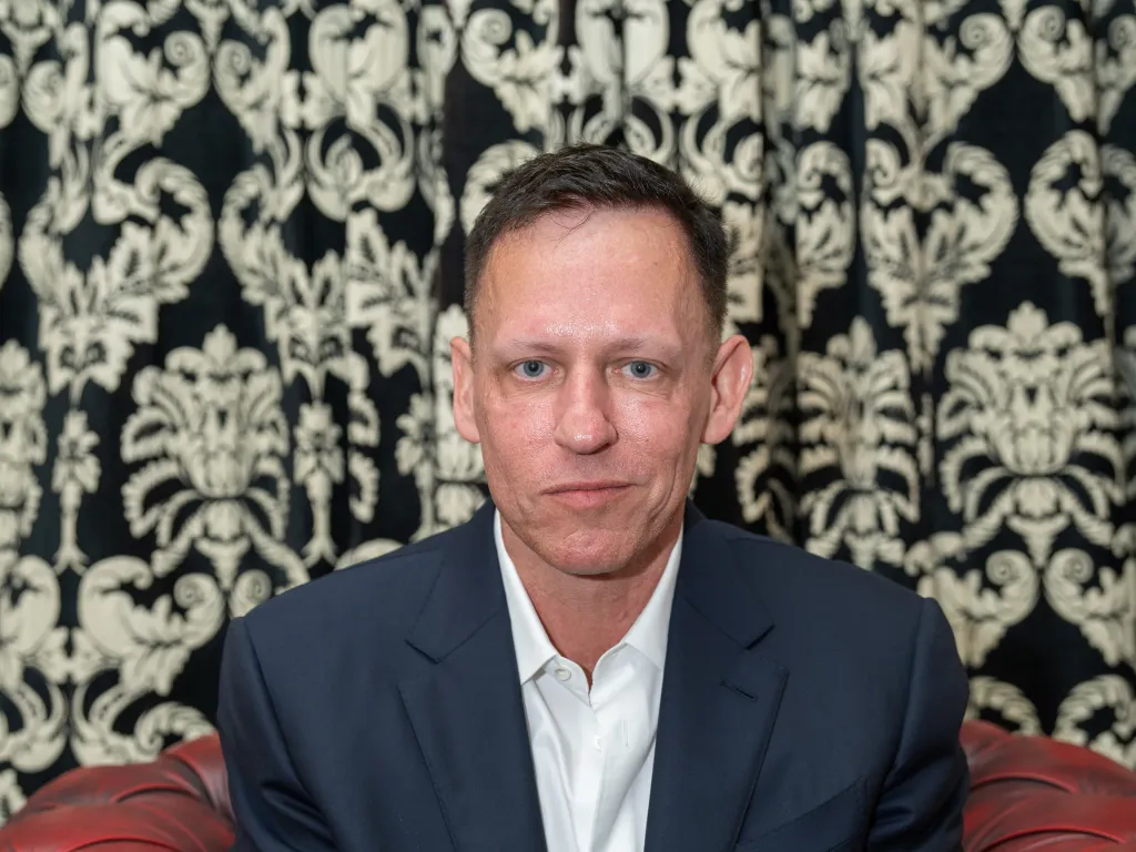 Peter Thiel in a dark suit jacket and white shirt, speaking at the Cambridge Union.