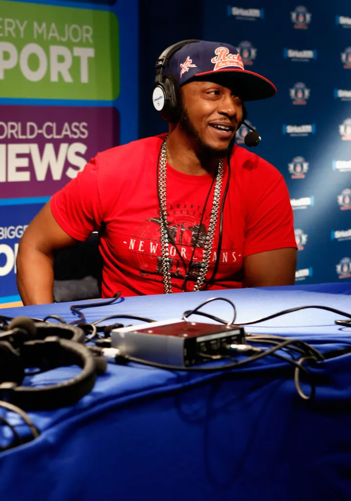 Musician Mystikal in a red t-shirt, headphones, and baseball cap attending SiriusXM's Live Broadcast from Radio Row.