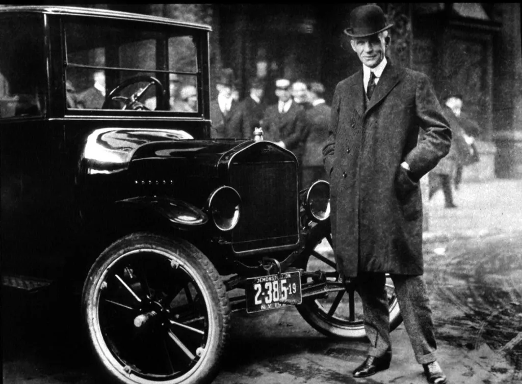 Henry Ford standing next to a Model T car.