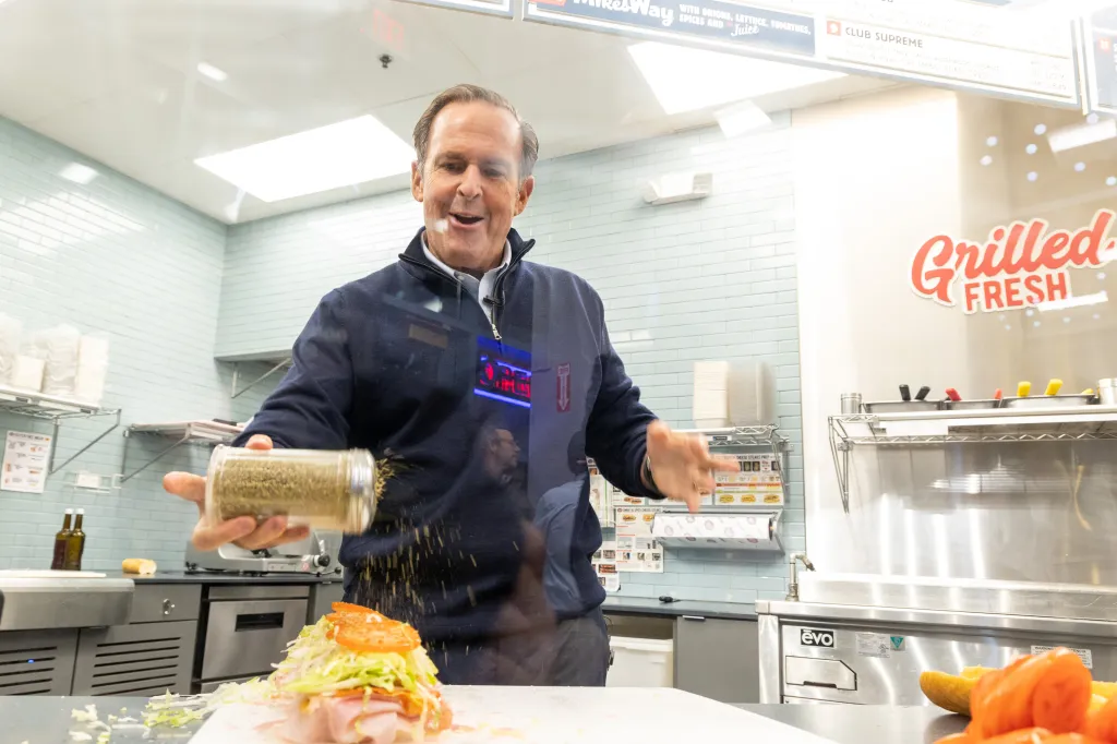Peter Cancro sprinkling spices on a sandwich at Jersey Mike's.