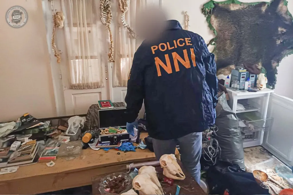 A police officer in a room with skeletons, animal skulls, and what appears to be a preserved animal skin hanging on the wall.